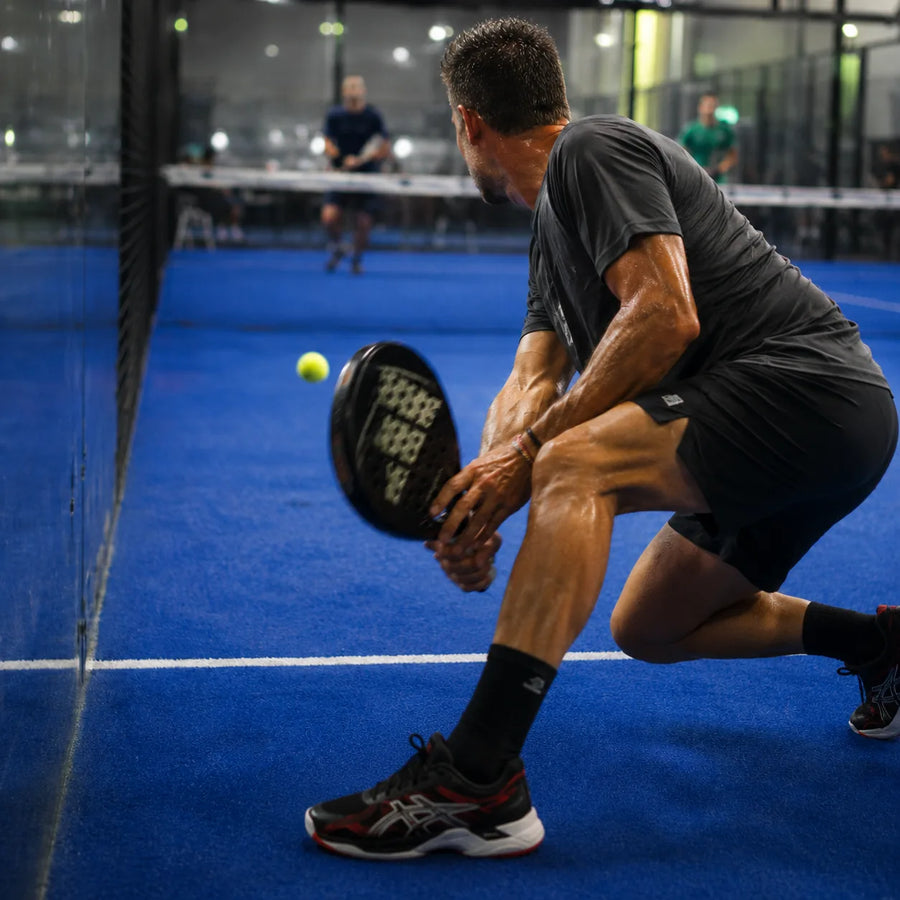 Padel player in a deep lunge, foot loaded on a hard cut